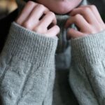 Warm and soft hands tucked into a knitted turtleneck sweater for a cozy winter feel.